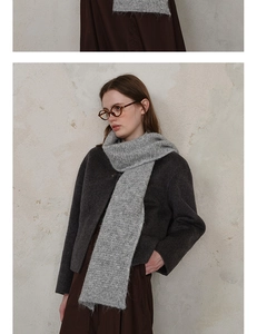 Detailed texture of gray diamond knit scarf paired with a wool coat in a retro style