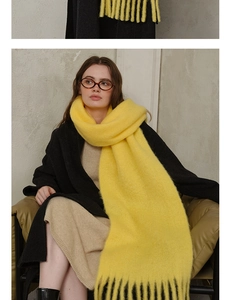 Close-up of bright yellow wool blend scarf showing soft knit texture and fringe detail