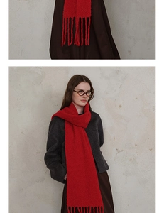 Detail of red wool blend knit scarf featuring textured bouclé yarn and tassel edges