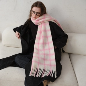 Pink and white checkered wool scarf with fringes worn over a long black winter coat