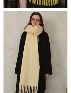Detail of light yellow wool blend scarf with long tassels and soft fluffy texture