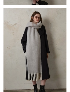 Detail of thick light grey wool scarf showing soft texture and long handmade tassels