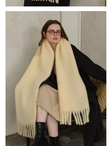 Detail view of a soft beige wool blend scarf with fringe tassels for winter warmth