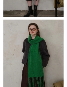 Detail of chunky knit wool scarf in vibrant green featuring long decorative fringe