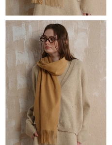 Close-up of ginger yellow wool scarf showing soft cashmere texture and fringe tassels