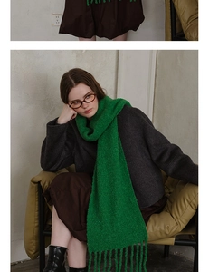 Close-up of emerald green wool knit scarf with tassel details on a winter coat