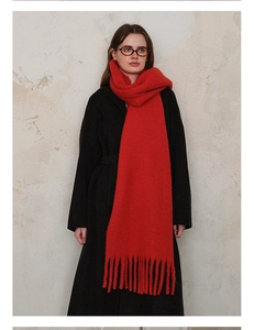 Detailed view of red wool blend scarf with thick tassels styled on a black coat