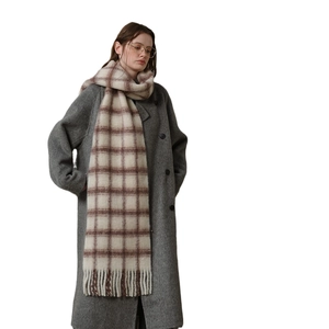 Soft pink plaid wool scarf with tassels paired with grey tweed coat on white background