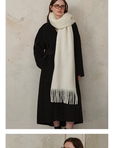 Detail of cream white wool blend scarf with fringe paired with a black wool coat