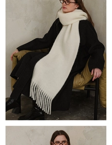 Close-up of cream wool blend scarf showing thick knit texture and long fringe details