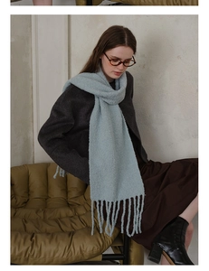Detail shot of light blue wool-blend knitted scarf featuring long decorative fringe tassels