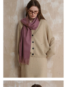 Detail of soft purple wool scarf with long tassels draped over a beige cardigan