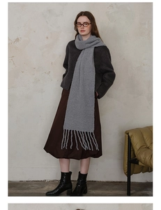 Detail of light gray knit wool scarf showing soft plush texture and long fringe tassels