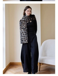Detail of a thick leopard print scarf styled with a black outfit in a modern setting