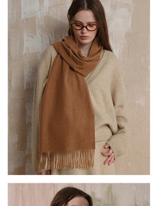 Close-up of brown wool scarf with tassel detail worn with a beige knit outfit