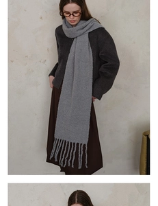 Close-up of light grey wool blend knit scarf featuring textured fringe detail on model