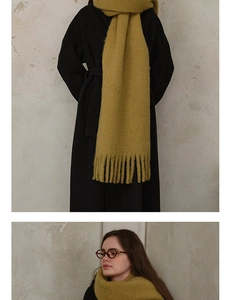 Detail of mustard yellow wool blend scarf with fringe paired with a black wool coat