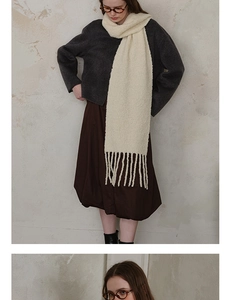 Close-up of cream wool blend knit scarf showing textured boucle fabric and long tassels