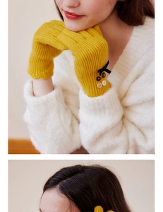 Detail of yellow knit gloves featuring black bow decoration and vintage style buttons