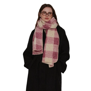 Pink and beige plaid scarf with stitched edges worn over a long black winter coat