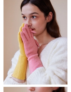 Close-up of long wool knit gloves featuring bright yellow and pink color-blocking design