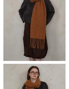 Close-up detail of warm brown wool knit scarf showing thick tassel and textured pattern