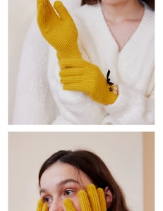 Detail of yellow knit wool gloves featuring black bow and colorful button accents
