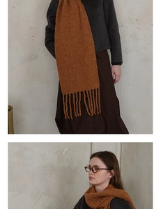 Close-up of brown wool knit scarf texture featuring long tassels and soft draping effect