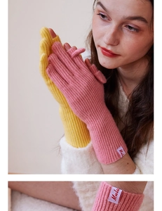Close-up of knit wool gloves showing ribbed texture and brand label in pink and yellow