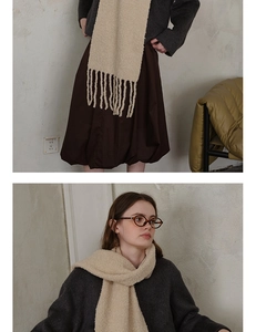 Detail of beige knit wool scarf with long tassels paired with dark grey winter coat