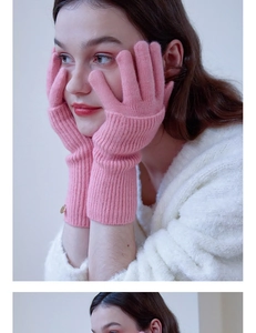 Close-up of pink wool knitted gloves with ribbed cuffs and decorative metal button detail