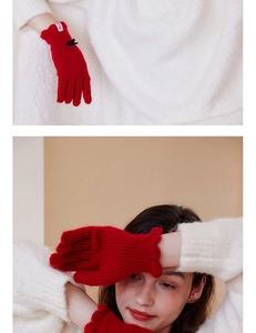 Detail of red wool knit gloves with black bow accent and ruffled cuffs for winter warmth