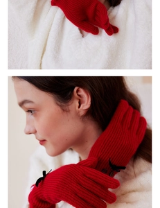 Detail of red wool blend gloves with black bow and buttons on white knit background