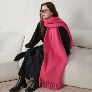 Vibrant hot pink wool blend scarf with long tassels worn by a model in a minimal setting