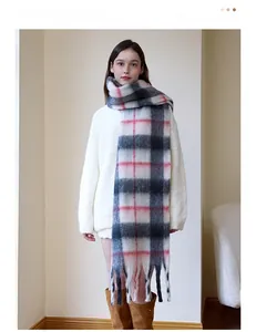 Thick plaid knit scarf with long tassels in grey white and red tones on a model
