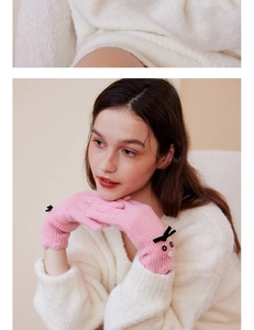 Detail of pink knitted wool gloves with cute cat motif and bow for winter warmth