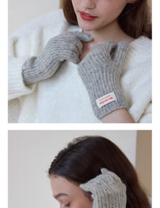 Close-up of light grey ribbed knit winter gloves with minimalist brand logo tag detail