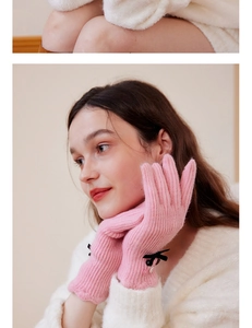 Pink wool knit glove detail featuring striped texture, black bow, and pearl decoration
