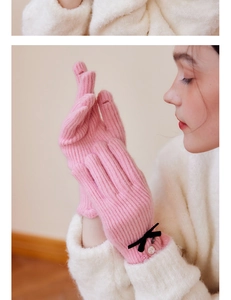 Detail of pink wool knit glove featuring elegant black satin bow and decorative buttons