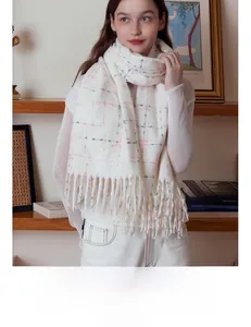 Detail showing soft cream plaid scarf texture and fluffy fringe in cozy home setting