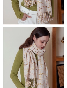 Detail of cream plaid scarf with orange stripes and long tassel fringe for winter fashion