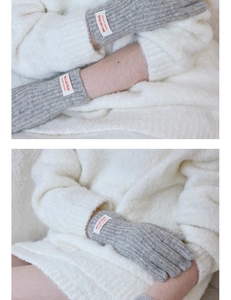 Macro detail of gray knitted touch screen gloves with vertical ribbed texture and brand tag