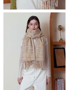Close-up of soft beige plaid scarf with long fringe detail and woven wool texture