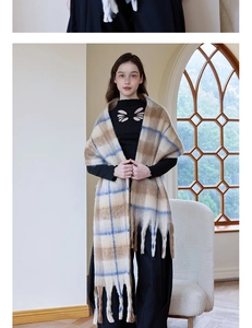 Detail of the thick checkered cashmere scarf featuring blue and beige patterns and tassels
