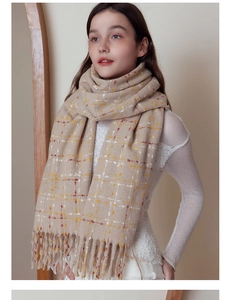 Detail of soft cream plaid scarf with fringe tassels and warm textured knit fabric