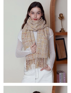 Detail of beige plaid scarf with thick fringe on a soft winter cashmere-like fabric