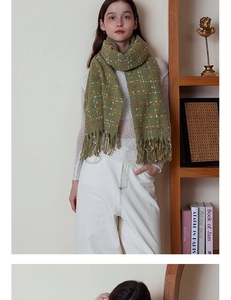 Close-up of olive green plaid cashmere scarf featuring soft tassels and retro knit pattern