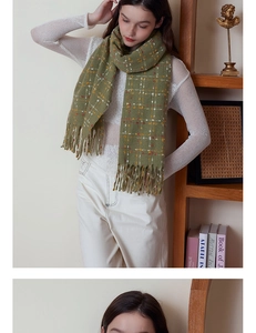 Detail of olive green plaid cashmere scarf with long tassels worn by a model in winter