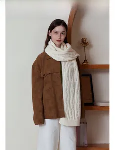 Close-up of white cable knit scarf details paired with a brown suede collar jacket