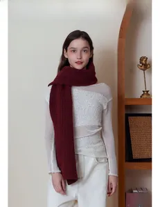 Détail de la texture d'une écharpe en tricot bordeaux portée par un mannequin femme